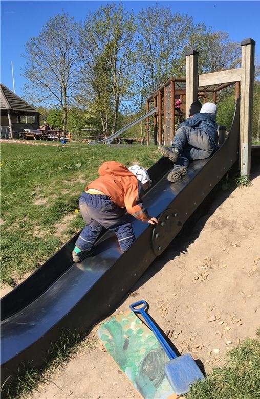 Billede af to børn, der kravler op af en rutchebane på børnehavens legeplads.